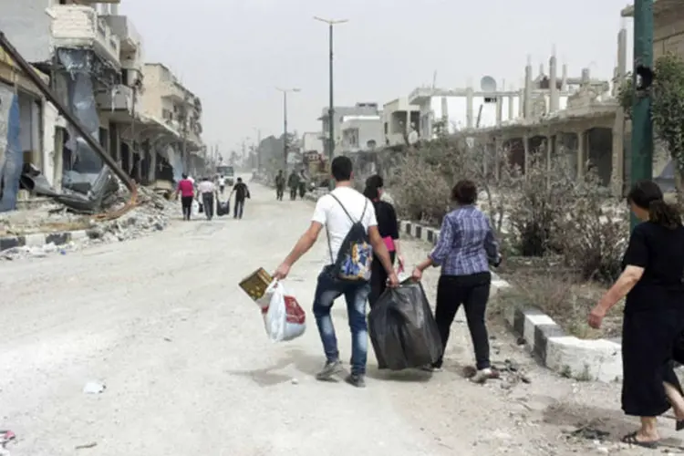 Moradores sírios da cidade de Qusair carregam bolsas com pertences, na Síria (Rami Bleibel/Reuters)