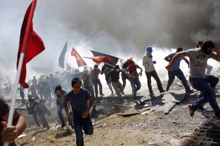 
	Manifestantes correm enquanto policiais lan&ccedil;am g&aacute;s lacrimog&ecirc;neo durante protesto na Pra&ccedil;a Taskim, em 11 de junho: tens&atilde;o pode aumentar devido greve e manifesta&ccedil;&otilde;es convocadas para hoje
 (Murad Sezer/AFP)