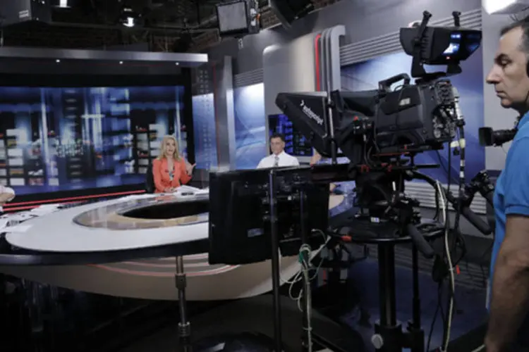 Cinegrafista filma a apresentadora Elli Stai (centro) durante boletim de notícias na sede da emissora ERT em Atenas, na Grécia, nesta terça-feira (John Kolesidis/Reuters)