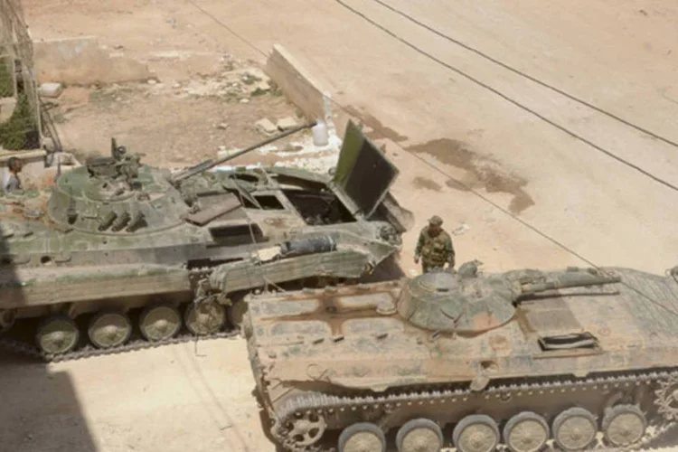 Soldados do exército sírio perto de tanque de guerra se preparam para uma ofensiva na zona rural de Alepo, na Síria (George Ourfalian/Reuters)
