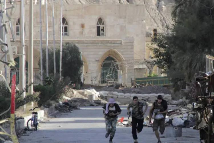 Membros do exército livre da Síria correm para evitar um atirador de elite na cidade de Deir al-Zor (Khalil Ashawi/Reuters)