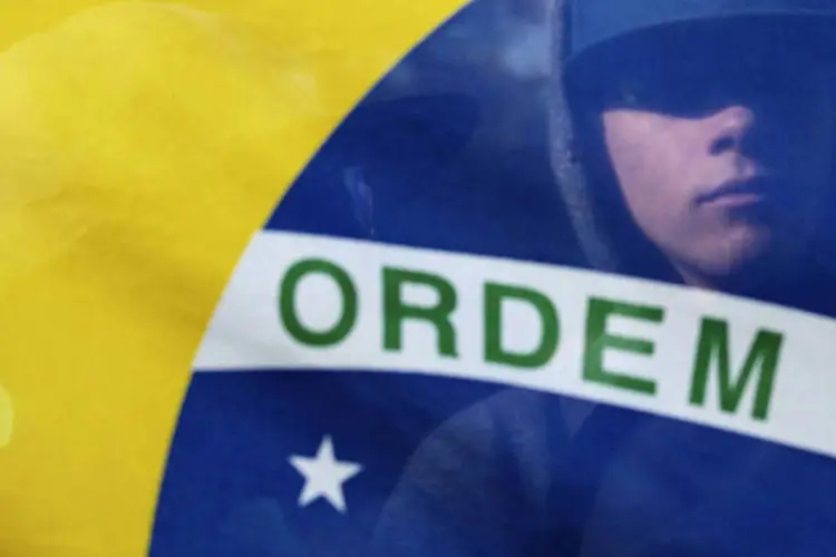 
	Manifestante &eacute; visto atr&aacute;s da bandeira do Brasil durante protestos: h&aacute; atos previstos em v&aacute;rias cidades
 (Alex Almeida/Reuters)