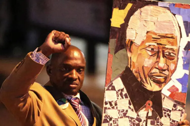 
	Repetindo gesto do punho fechado, homem exibe retrato de Mandela em frente hospital: informa&ccedil;&otilde;es mais recentes indicam que o ex-presidente se mant&eacute;m em estado cr&iacute;tico e est&aacute;vel
 (Siphiwe Sibeko / Reuters)