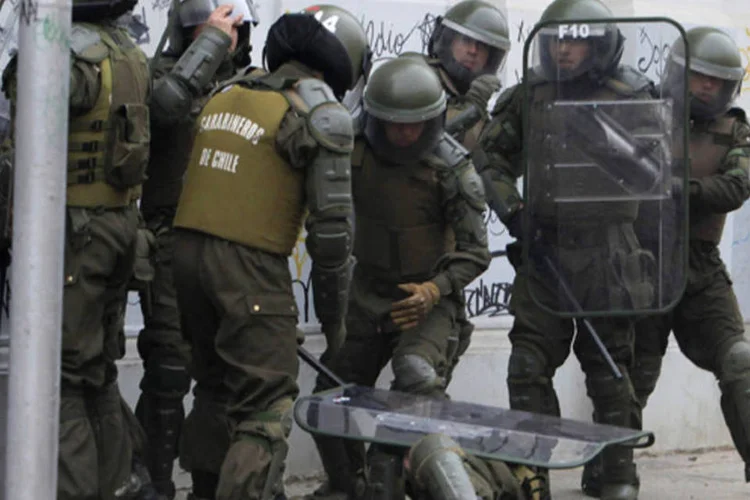 Policial da tropa de choque cai durante manifestação contra o governo em Santiago, Chile (Carlos Vera/Reuters)