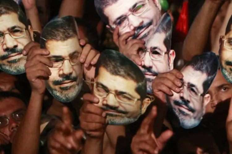 Membros e apoiadores da Irmandade Mulçumana, partido do presidente egípcio deposto, Mohamed Mursi, seguram máscara com de Mursi na praça Rabaa Adawiya, no Cairo (Mohamed Abd El Ghany/Reuters)