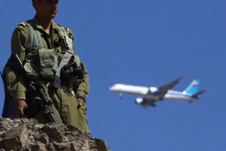 Avião voa enquanto um soldado monta guarda próximo da fronteira entre Israel e Egito, em Eilat (Ronen Zvulun/Reuters)