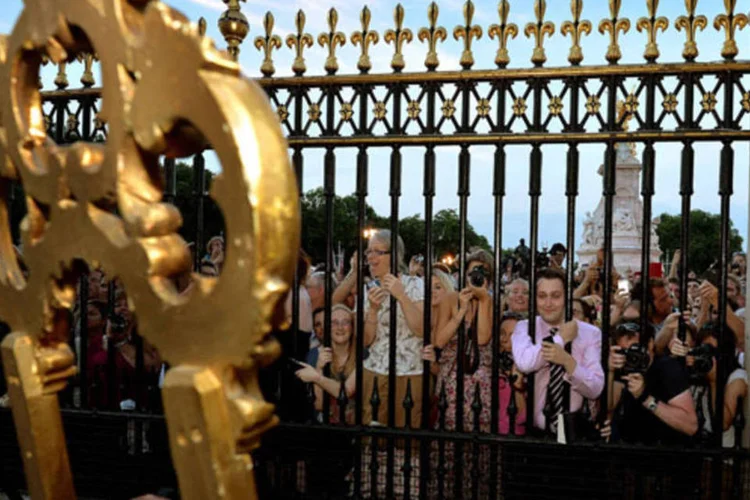 Multidão tenta ler o anúncio oficial do nascimento do filho de William e Kate em frente ao palácio de Buckingham, em Londres (John Stillwell/Reuters)