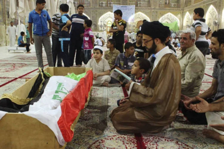 Pessoas rezam no funeral de uma vítima morta durante ataque a uma prisão em Taji, ao sul de Bagda (Haider Ala/Reuters)