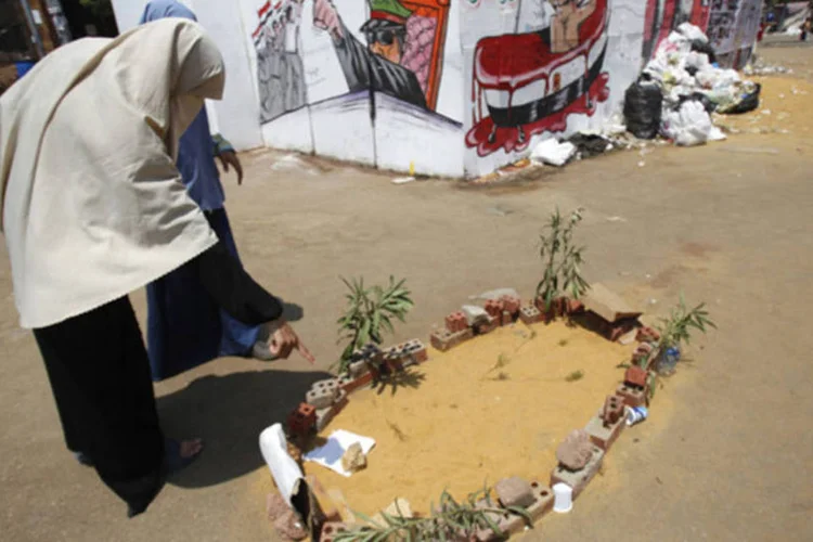 Apoiadora do presidente deposto do Egito, Mohamed Mursi, aponta para túmulo simbólico de manifestante morto durante conflitos com opositores próximo à Universidade do Cairo (Amr Abdallah Dalsh/Reuters)