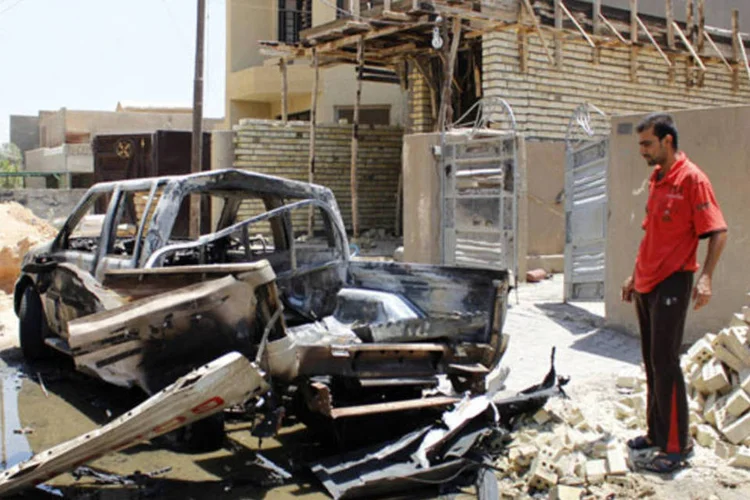 Homem olha os destroços de um veículo danificado por um ataque a bomba, do lado de fora de um mesquita sunita no sul do distrito de Doura, em Bagdá (Ahmed Saad/Reuters)