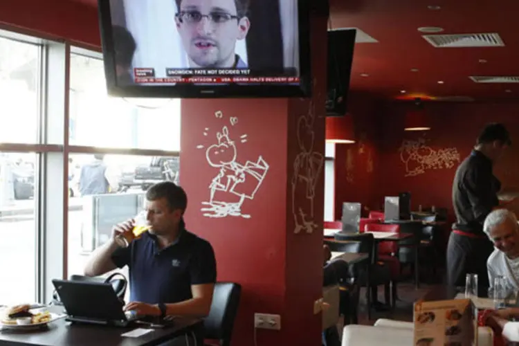 
	Televis&atilde;o mostra Edward Snowden durante um boletim de not&iacute;cias no aeroporto de Moscou: rea&ccedil;&otilde;es entre R&uacute;ssia e EUA ficaram ainda mais baladas ap&oacute;s asilo ao ex-agente da NSA
 (Tatyana Makeyeva/Reuters)