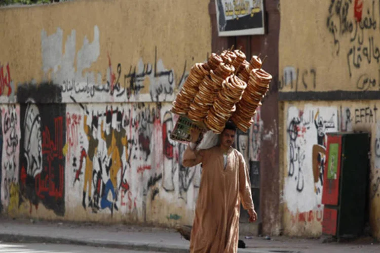 
	Vendedor de rua caminha com p&atilde;o em uma rua pr&oacute;xima da pra&ccedil;a Tahrir, em Cairo
 (Amr Abdallah Dalsh/Reuters)