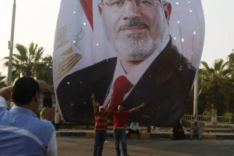 Apoiadores do presidente deposto do Egito Mohamed Mursi posa para fotos junto a um cartaz com seu rosto, próximo ao local de uma vigília ao redor da mesquita Raba' Al Adawya, no leste do Cairo (Asmaa Waguih/Reuters)