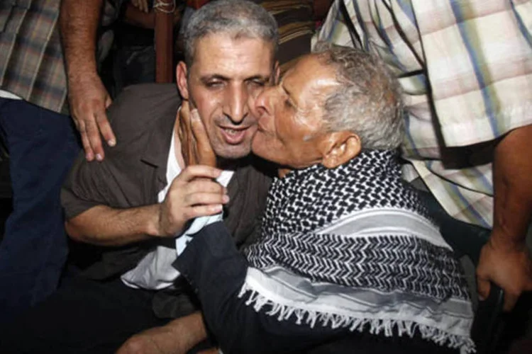 Ateya Abu Moussa, que foi libertado por Israel após 20 anos preso, é beijado por seu pai após sua chegada em Khan Younis, ao sul de Gaza (Ibraheem Abu Mustafa/Reuters)
