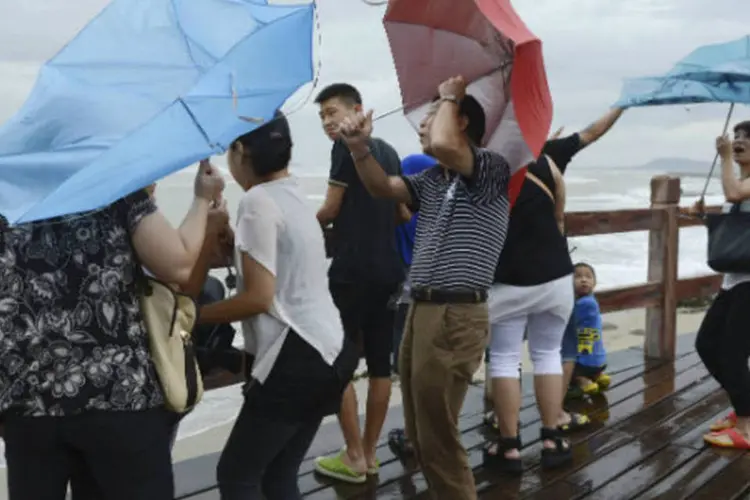 
	Pessoas tentam segurar os guardas-chuva em meio aos fortes ventos provocados pelo tuf&atilde;o Utor
 (Stringer/Reuters)