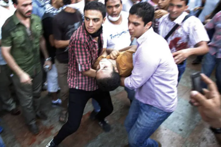 Manifestantes que apoiam o presidente deposto do Egito Mohamed Mursi levam manifestante ferido durante confronto na praça Ramsés, no Cairo (Amr Abdallah Dalsh/Reuters)