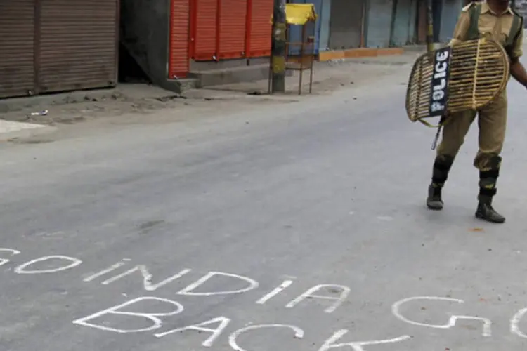 Foto de arquivo mostra um policial indiano patrulhando uma estrada pichada por manifestantes da Cashimira, após o toque de recolher em Srinagar (Fayaz Kabli/Reuters)