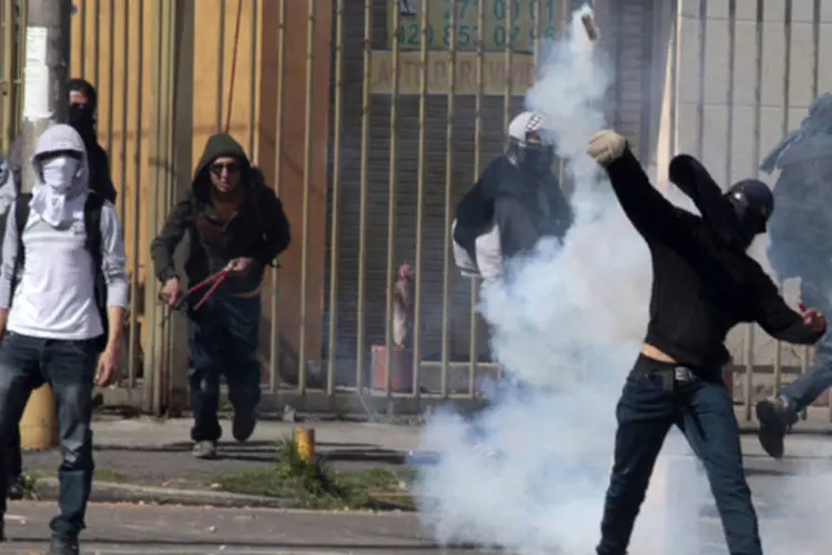 Estudante lança uma bomba de gás lacrimogêneo durante confronto com a polícia após protestos em Bogotá, na Colômbia (Jose Miguel Gomez/Reuters)