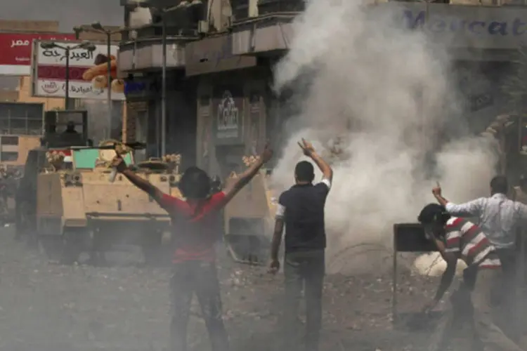 Apoiadores do presidente egípcio Mohamed Mursi jogam pedras na tropa de choque da polícia durante confronto na praça Rabaa Adawiya, em Cairo (Asmaa Waguih/Reuters)