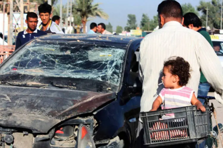 
	Moradores passam por carro danificado em Al Tabj: oficial da pol&iacute;cia morreu e outros dois ficaram feridos na explos&atilde;o de uma bomba na cidade
 (Mohammed Adnan/Reuters)