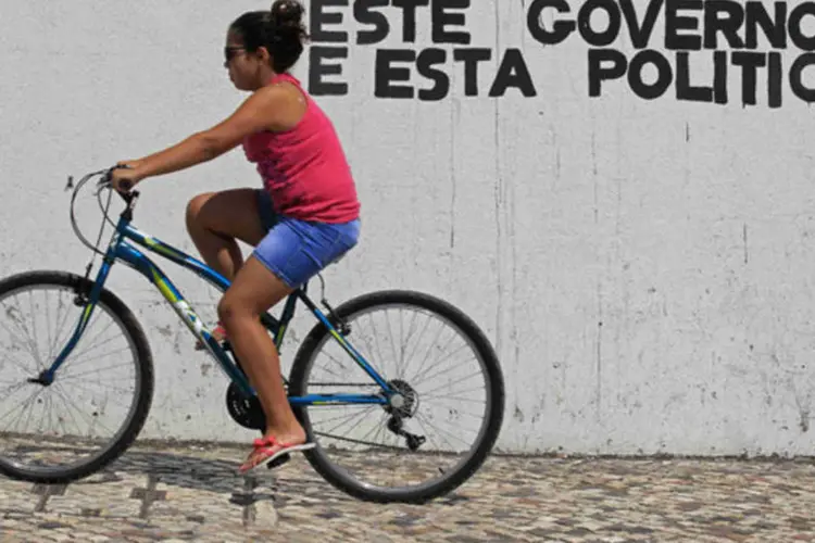 Ciclista passa por um graffiti de protesto contra o governo na Vila de Cacem, na periferia de Lisboa (Jose Manuel Ribeiro/Reuters)