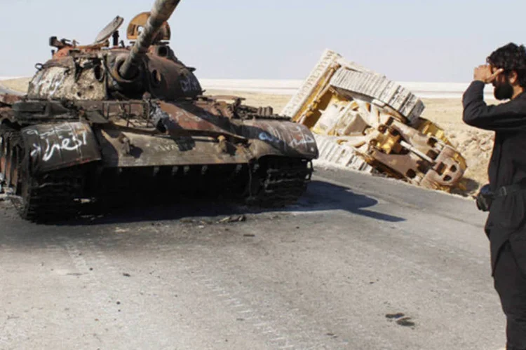 Membro do Exército Livre da Síria próximo de um tanque militar danificado que pertencia a forças fieis ao presidente Bashar Al-Assad, em Alepo (Molhem Barakat/Reuters)