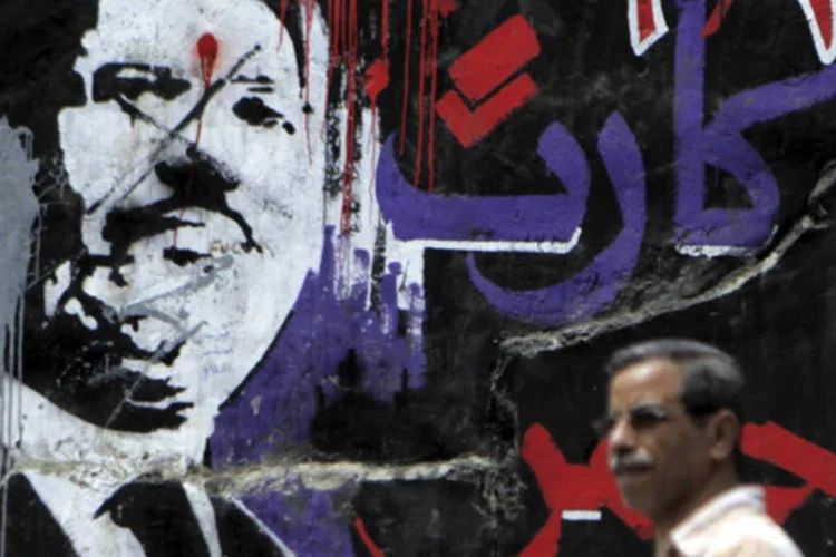 Homem caminha em frente a um grafite do presidente deposto do Egito Mohamed Mursi, no Cairo (Amr Abdallah Dalsh/Reuters)