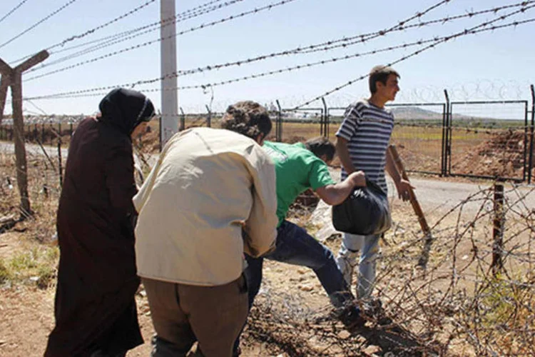 
	Refugiados s&iacute;rios cruzam a fronteira com a Turquia pr&oacute;xima da cidade de Azaz, na S&iacute;ria:&nbsp;muro ter&aacute; altura de dois metros, mas sua extens&atilde;o n&atilde;o foi divulgada
 (Molhem Barakat/Reuters)