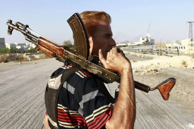 
	Combatente do Ex&eacute;rcito Livre da S&iacute;ria ergue sua arma ao caminhar pr&oacute;ximo ao aeroporto militar Nairab
 (Hamid Khatib/Reuters)