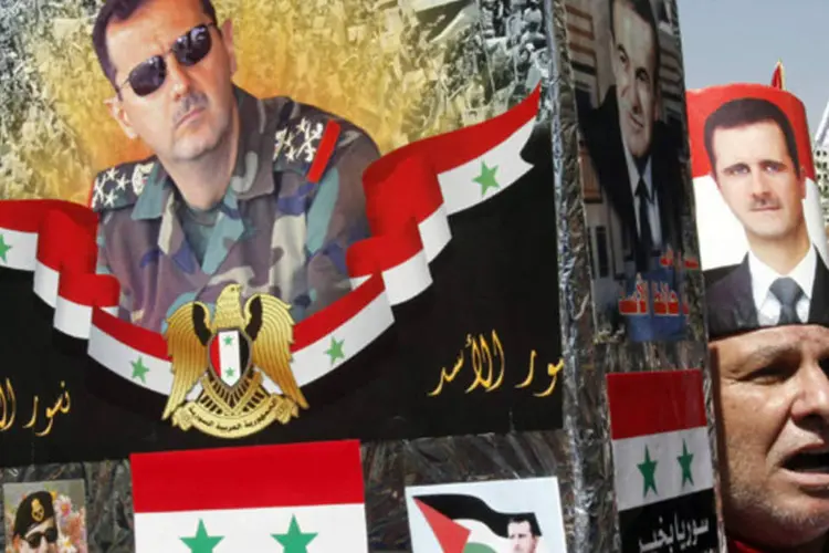 Apoiadores do presidente da Síria, Bashar al-Assad, segura imagens dele durante protesto contra possíveis ataques dos EUA a Síria, na praça Youssef al-Azma, em Damasco (Khaled al-Hariri/Reuters)