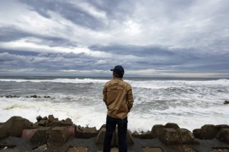 
	Homem observa ondas quebrando em barreira anti-tsunami em Fukushima: &aacute;rea para a qual alerta de tsunami &eacute; v&aacute;lido abrange complexo nuclear de Fukushima
 (Stringer/Reuters)