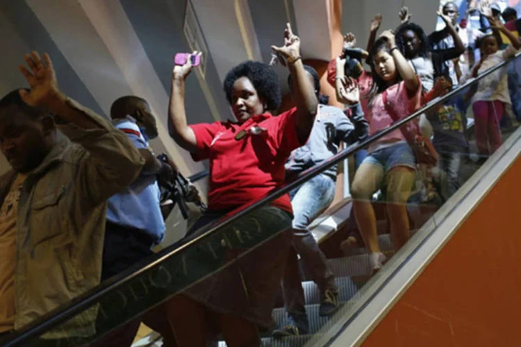 Policial armado é visto em meio a civis deixando á área de um shopping em Nairóbi, no Quênia, onde houve um ataque do grupo islâmico somali Al Shabaab (Siegfried Modola/Reuters)