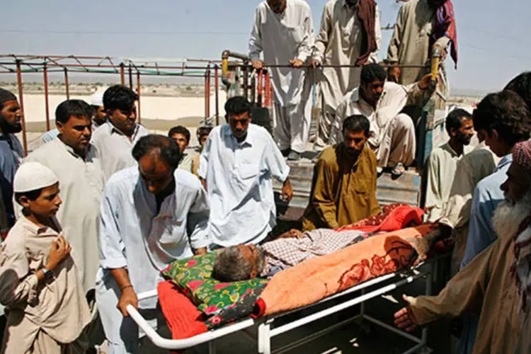 Sobreviventes de um terremoto no Paquistão ajudam a levar um homem ferido a hospital (REUTERS/Naseer Ahmed)