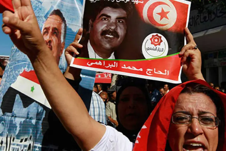 Manifestantes seguram foto de líder opositor para protestar contra o governo na Tunísia (Anis Mili/Reuters)