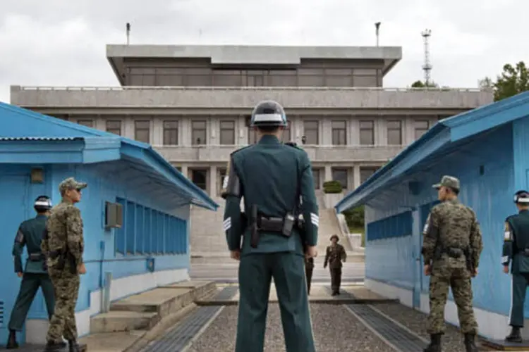 Soldados sul-coreanos olham para o lado norte-coreano enquanto soldados se aproximam de uma vila na Zona Desmilitarizada (Jacquelyn Martin/Reuters)