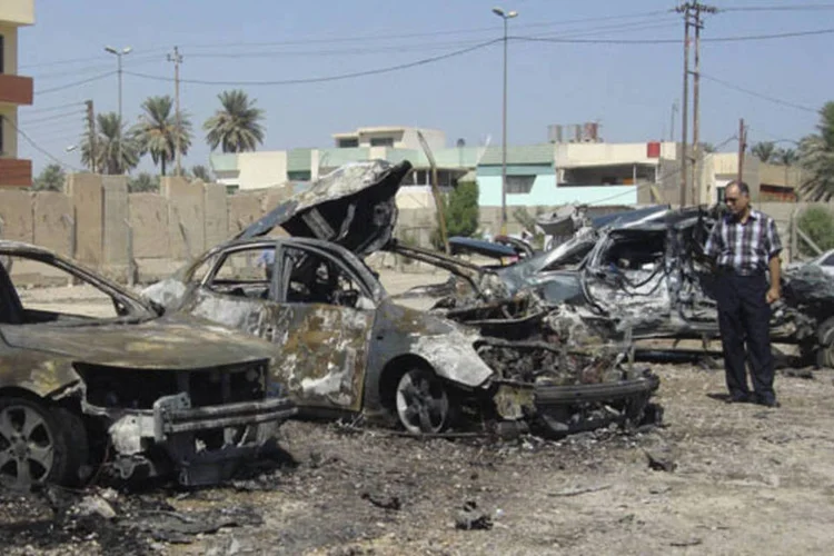 Homem examina carros destruídos no local de ataque com carro-bomba, no bairro de Kadhimiyam, em Bagdá (Hadeer Abbas/Reuters)