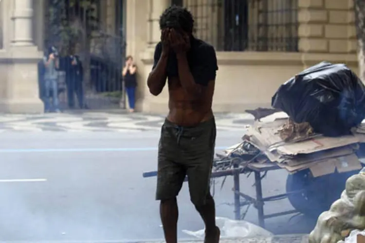 Manifestante protege o seu rosto de gás lacrimogênio durante confronto com policiais militares no Rio de Janeiro (Pilar Olivares/Reuters)