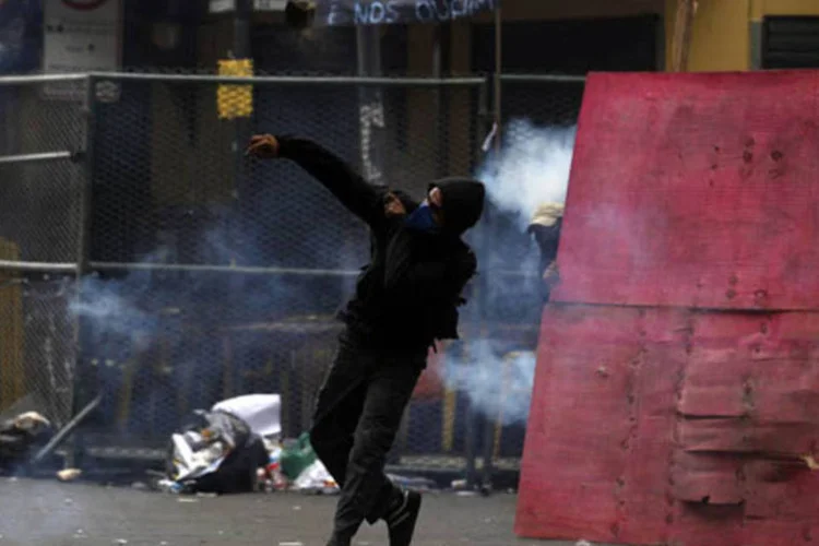 Manifestante joga pedra em policiais na frente da Câmara Municipal do Rio de Janeiro durante a greve dos professores (Pilar Olivares/Reuters)