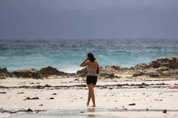 Mulher caminha em uma praia de Cancún, com nuvens ao fundo prenunciando a chegada da tempestade Tropical Karen, no Golfo do México (Victor Ruiz Garcia/Reuters)