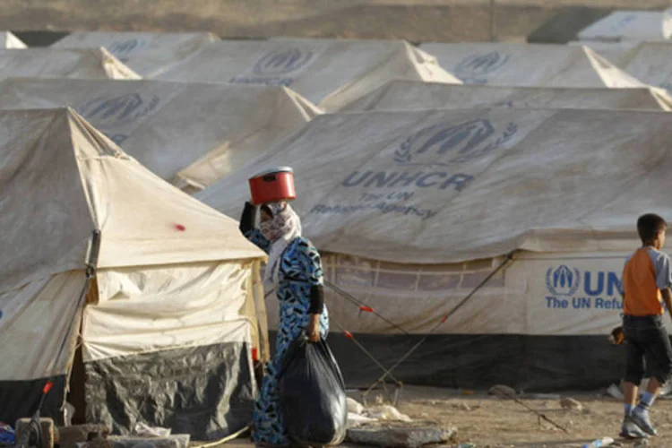 Refugiados sírios, em fuga da violência na Síria, caminham no campo de refugiados montados nos arredores da cidade de Arbil, no Iraque (Thaier al-Sudani/Reuters)
