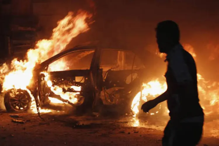 Homem olha para um carro pegando fogo no local de um ataque a bomba em Bagdá, no Iraque (Ahmed Saad/Reuters)