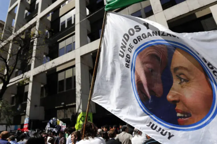 Homem segura bandeira com a foto da presidente argentina, Cristina Kirchner, junto com o falecido marido, Néstor Kirchner, em frente ao hospital onde ela está internada, em Buenos Aires (Marcos Brindicci/Reuters)