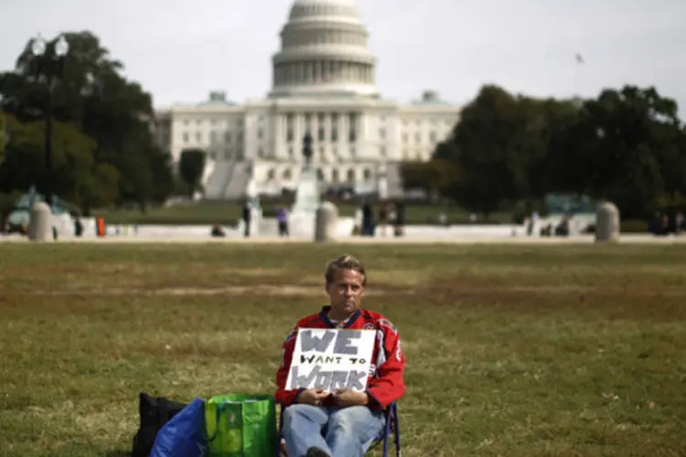 Funcionário público federal Jeffrey Wismer segura cartaz de protesto em que se lê "Queremos trabalhar", no gramado em frente ao Capitólio (Jason Reed/Reuters)