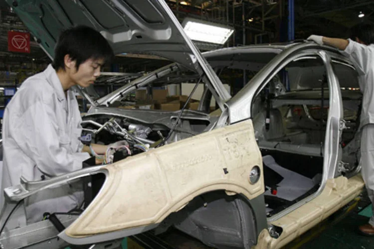Funcionários chineses da Peugeot trabalham na linha de montagem da fábrica da Dongfeng PSA Peugeot Citroen em Wuhan (Jacky Naegelen/Reuters)