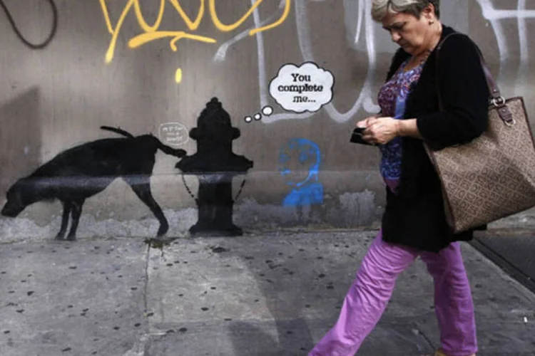 Mulher passa por um grafite do artista britânico Bansky em West 24th street, em Nova York (Mike Segar/Reuters)