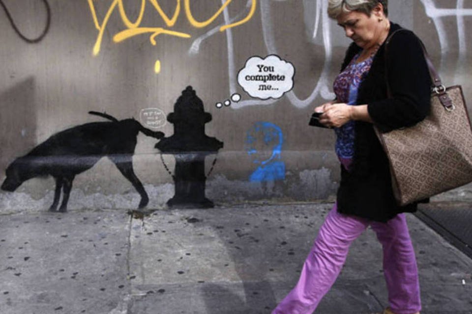 Mulher passa por um grafite do artista britânico Bansky em West 24th street, em Nova York (Mike Segar/Reuters)