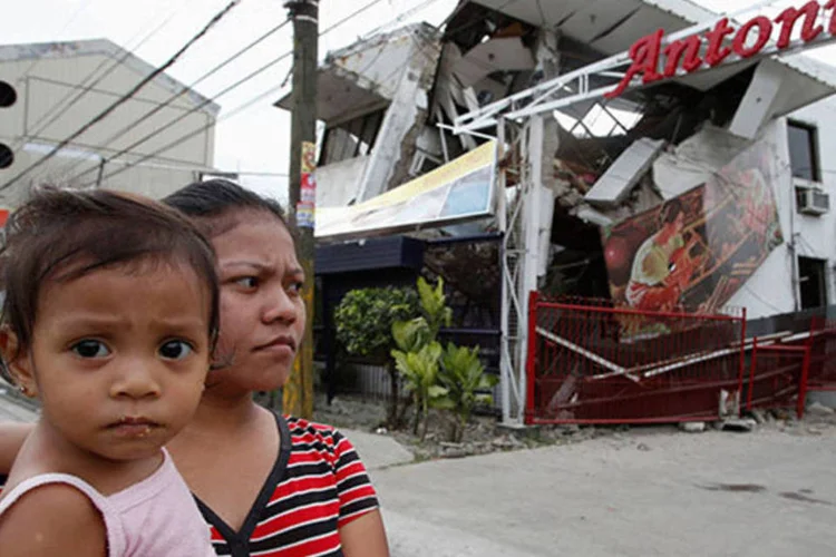 
	Uma mulher e sua filha passam por destro&ccedil;os deixados pela passagem de terremoto nas Filipinas: ao menos 100 pessoas ficaram feridas em Bohol
 (REUTERS/Erik De Castro)