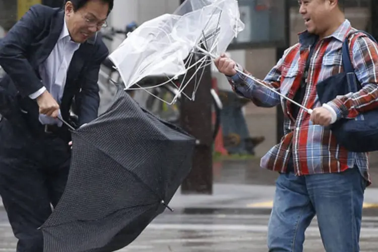 Japoneses tentam usar o guarda-chuva durante a passagem do tufão Wipha, no distrito comercial de Tóquio (Toru Hanai/Reuters)