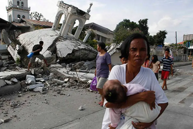 
	M&atilde;e segura o filho em frente a uma igreja destru&iacute;da por terremoto nas Filipinas: dos 99 mortos, 89 s&atilde;o da Ilha de Bohol, onde foi localizado o epicentro do tremor
 (REUTERS/Erik De Castro)