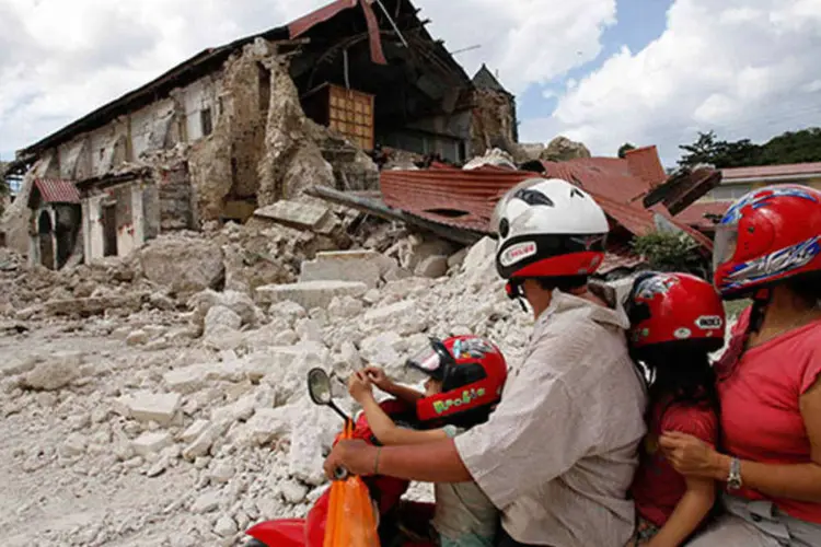 
	Uma fam&iacute;lia observa, de uma moto, igreja destru&iacute;da por terremoto nas Filipinas: um total de 17 igrejas hist&oacute;ricas ficaram danificadas
 (REUTERS/Erik De Castro)